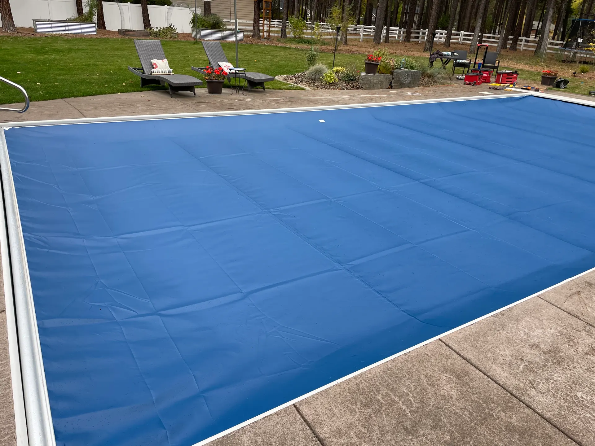 Blue automatic pool cover closed over a backyard swimming pool