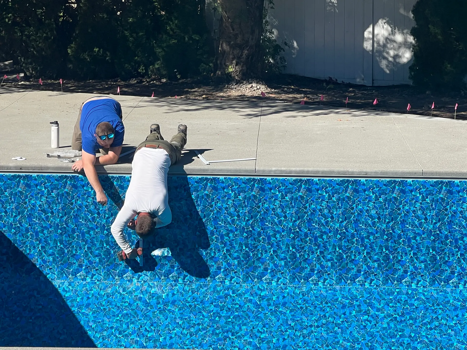 Crew stretching a new vinyl liner into the pool walls