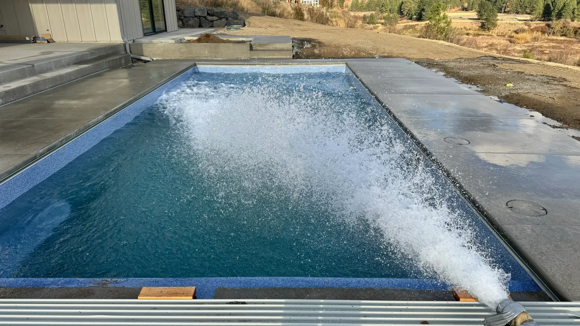 Fiberglass pool shell filling with water, splash from return jet