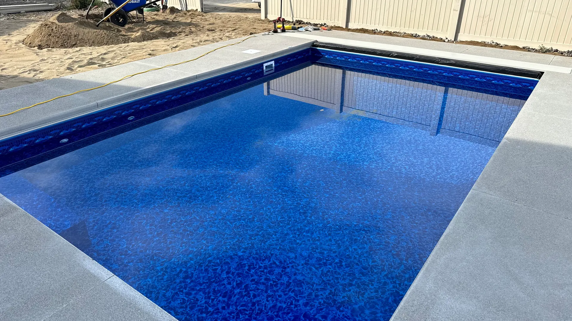 Finished pool with a blue automatic cover and visible cover track