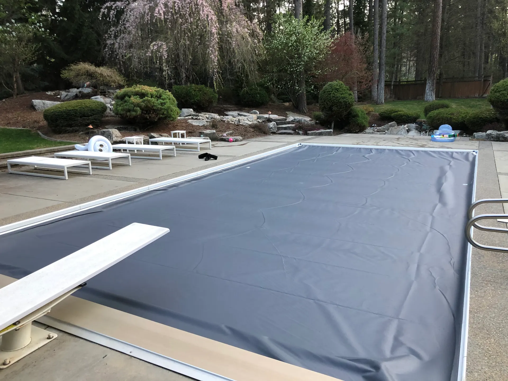 Gray automatic pool cover closed over a backyard pool and patio