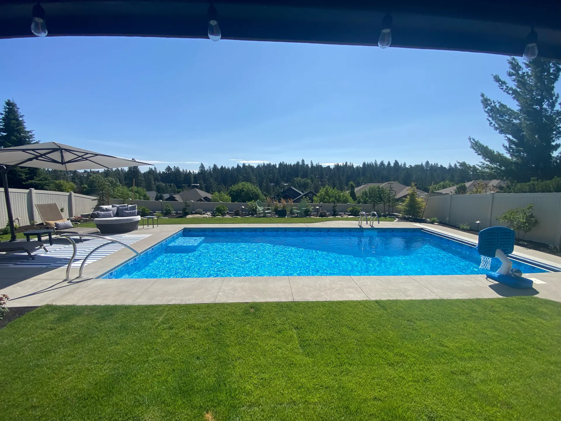 Hillside Spokane backyard pool with lawn, seating, and finished decking by Waterscape