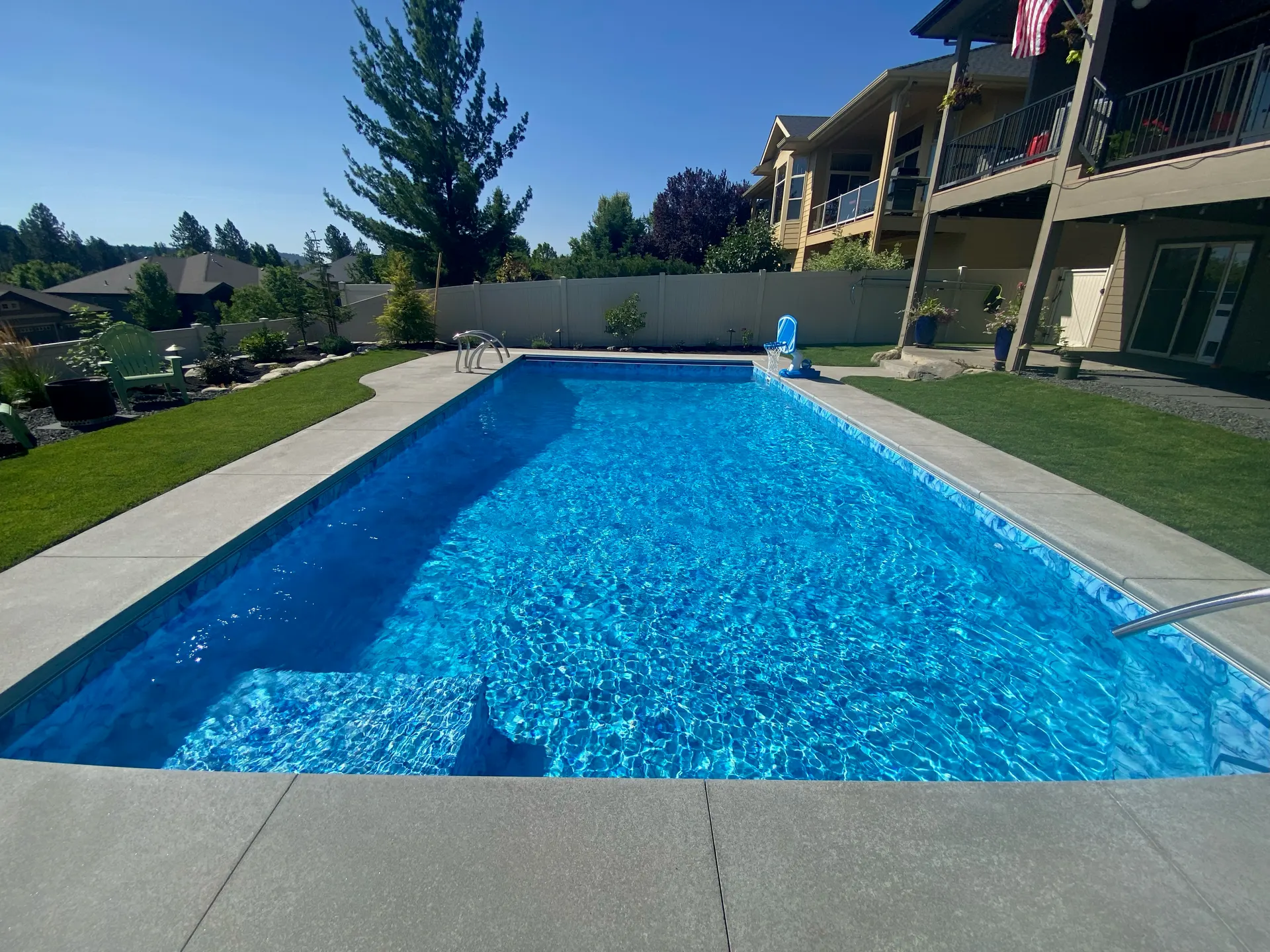 Long perspective of a hillside vinyl-liner pool with clear water and coping