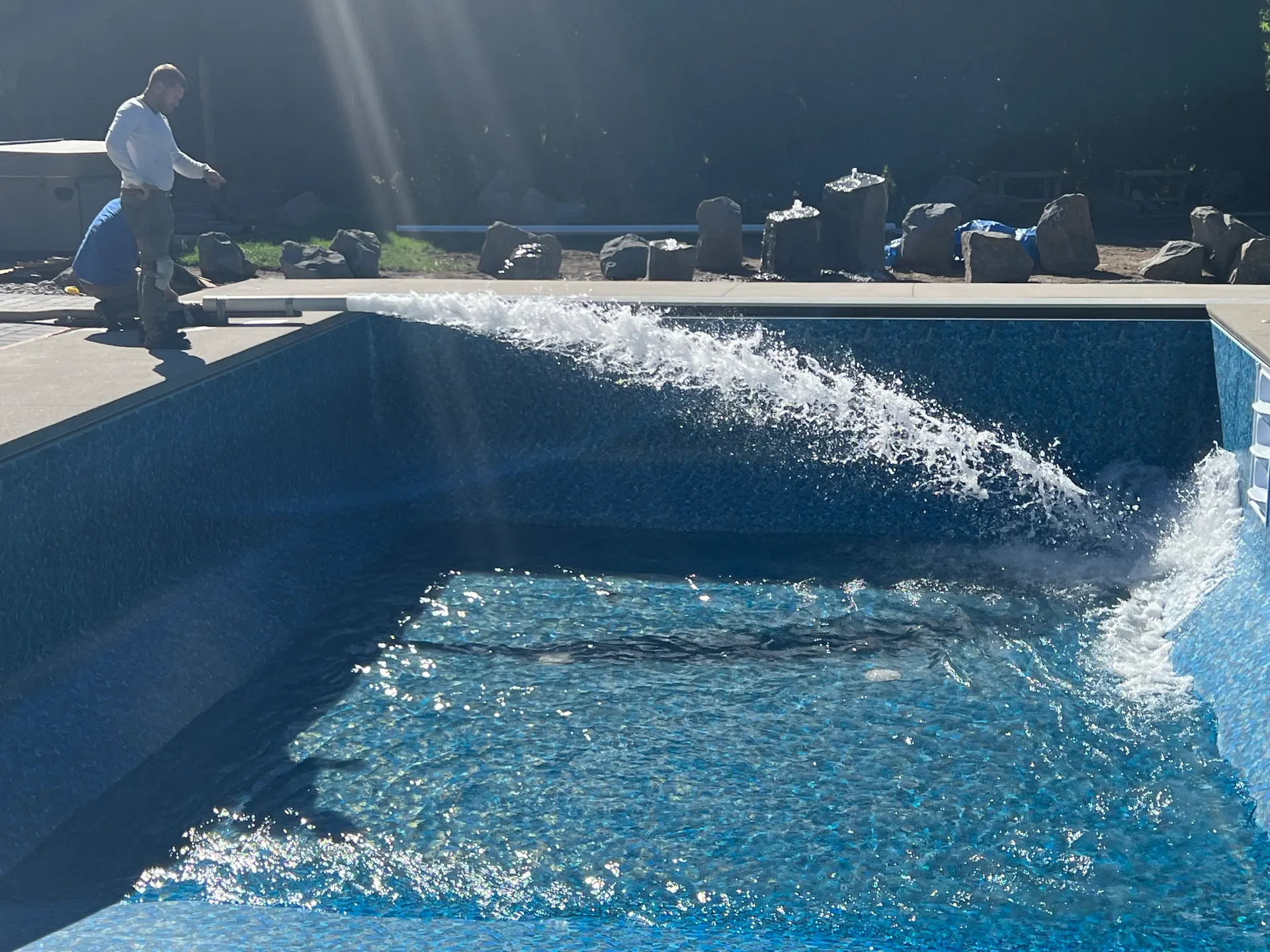 Vinyl-liner pool filling with water stream and installer in frame